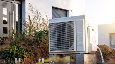A large air conditioner is sitting outside of a house.