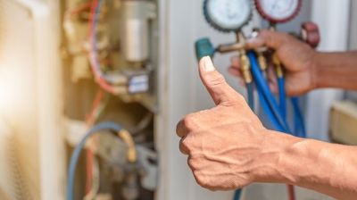 A person is giving a thumbs up while working on a machine.
