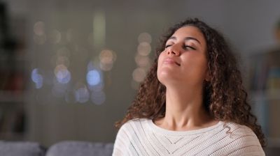 A woman is sitting on a couch with her eyes closed.