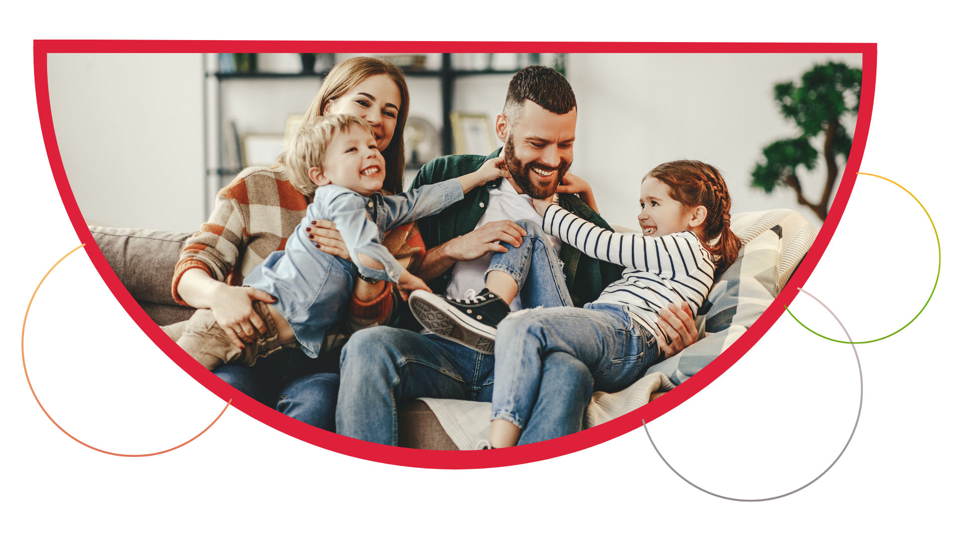 Family laughing on a couch. Two children playfully interact with their parents in a living room.