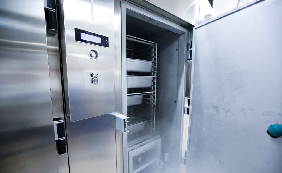 A stainless steel refrigerator with the door open and smoke coming out of it.