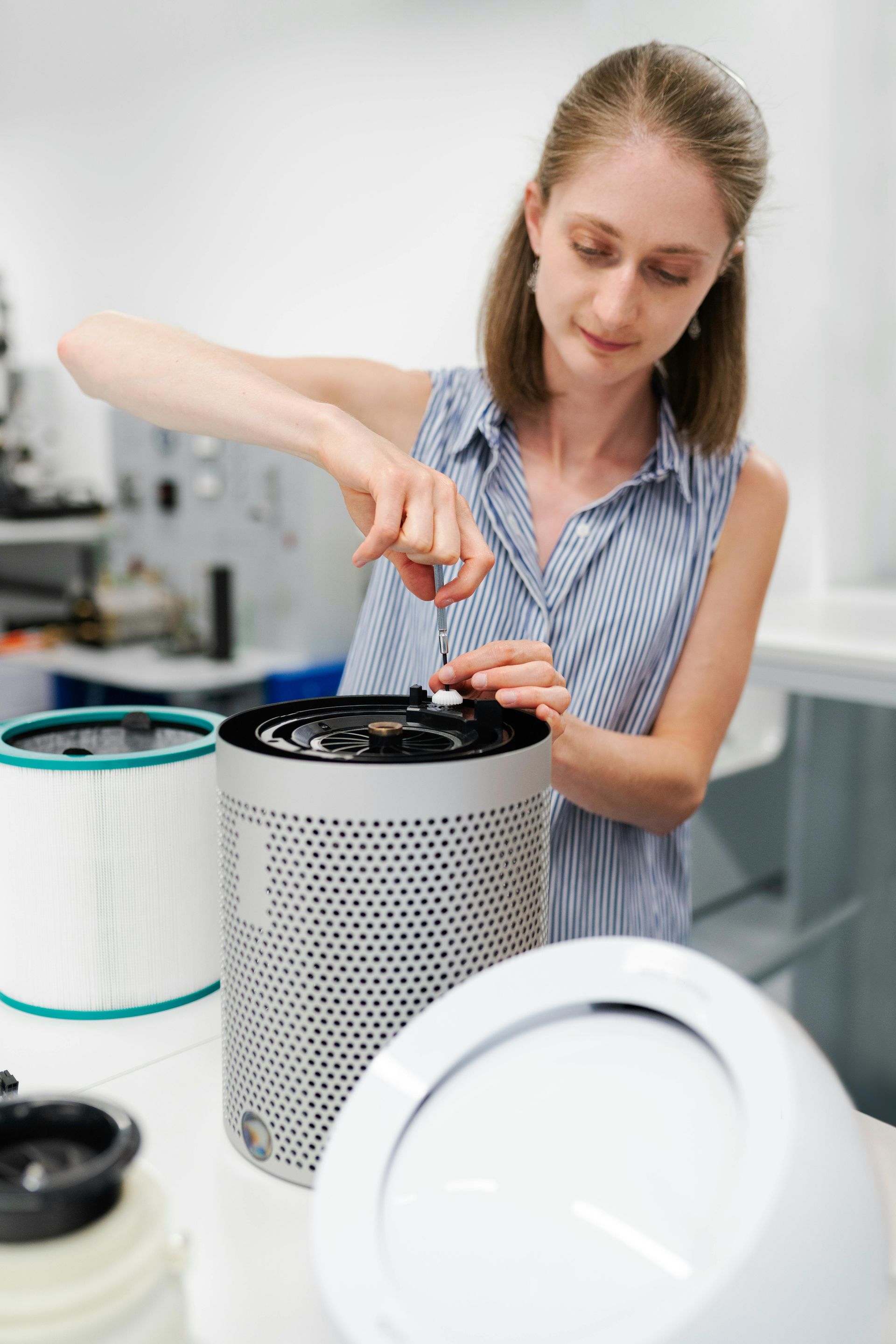 Woman assembling air purifier with screwdriver in a lab.