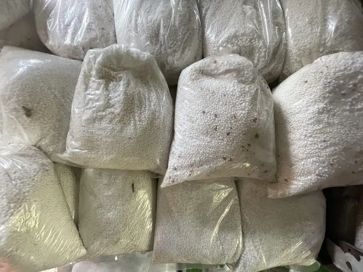 Un montón de bolsas de polvo blanco están apiladas una encima de otra.