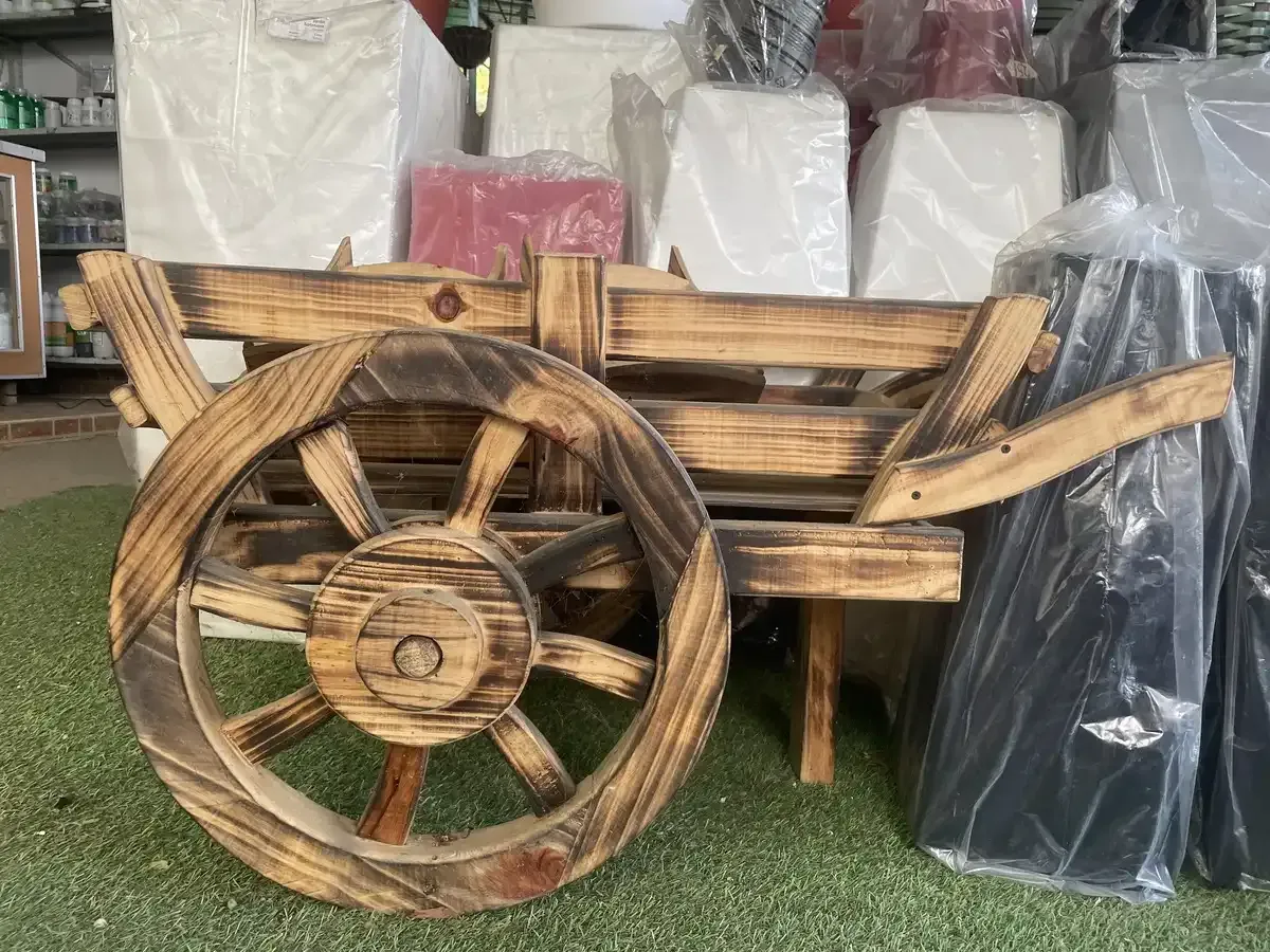 Una rueda de carro de madera sobre un campo verde.