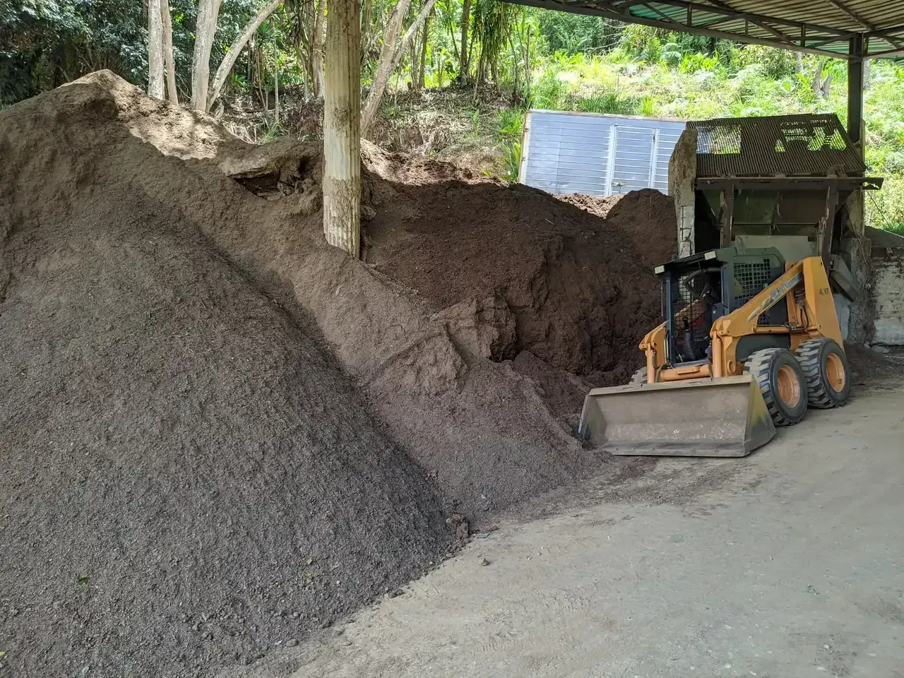Una excavadora está parada al lado de un montón de tierra.