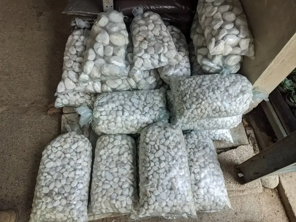 Una pila de bolsas de piedras blancas colocadas encima de un estante de madera.