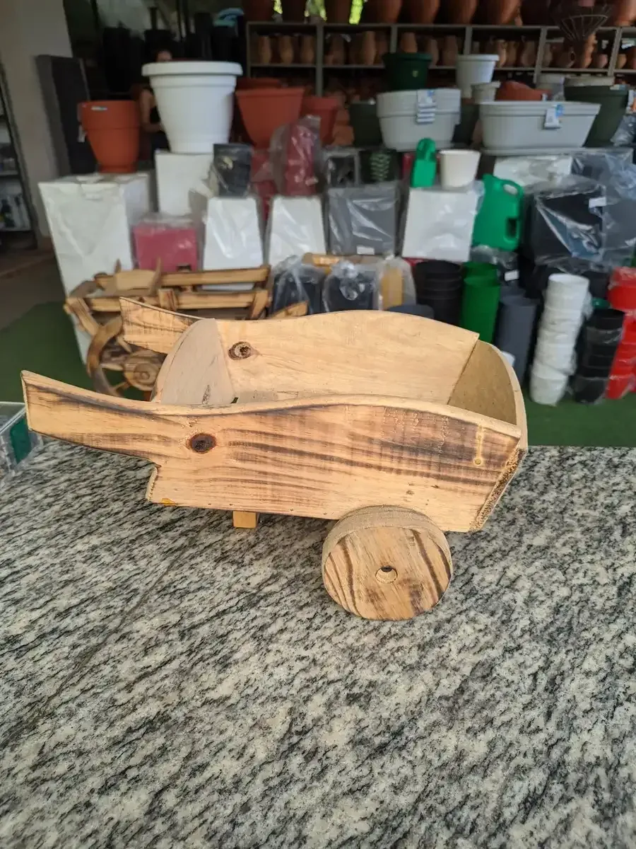 Una carretilla de madera está sobre una mesa delante de una pila de ollas.