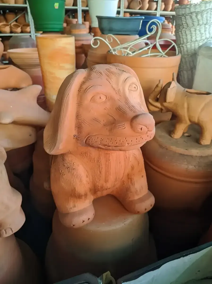 Una estatua de un perro está sentada encima de una pila de macetas.