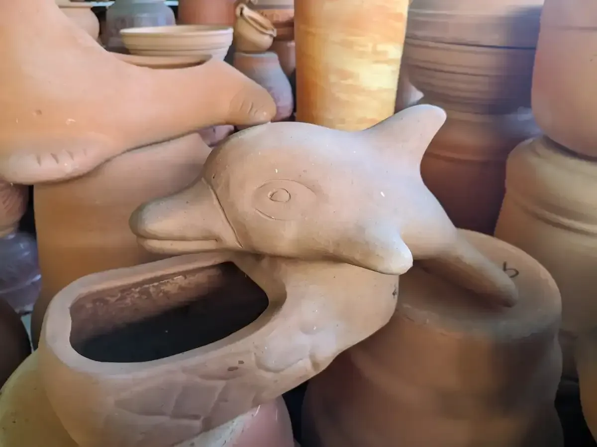 Vasija en forma de delfín puesto en otra vasija en una tienda de vasijas