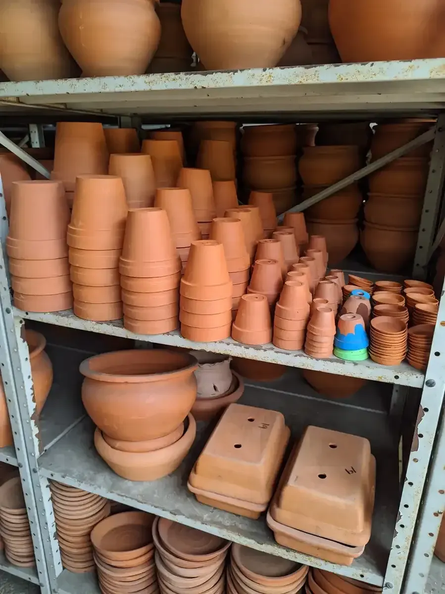 Un estante lleno de ollas y recipientes de barro.