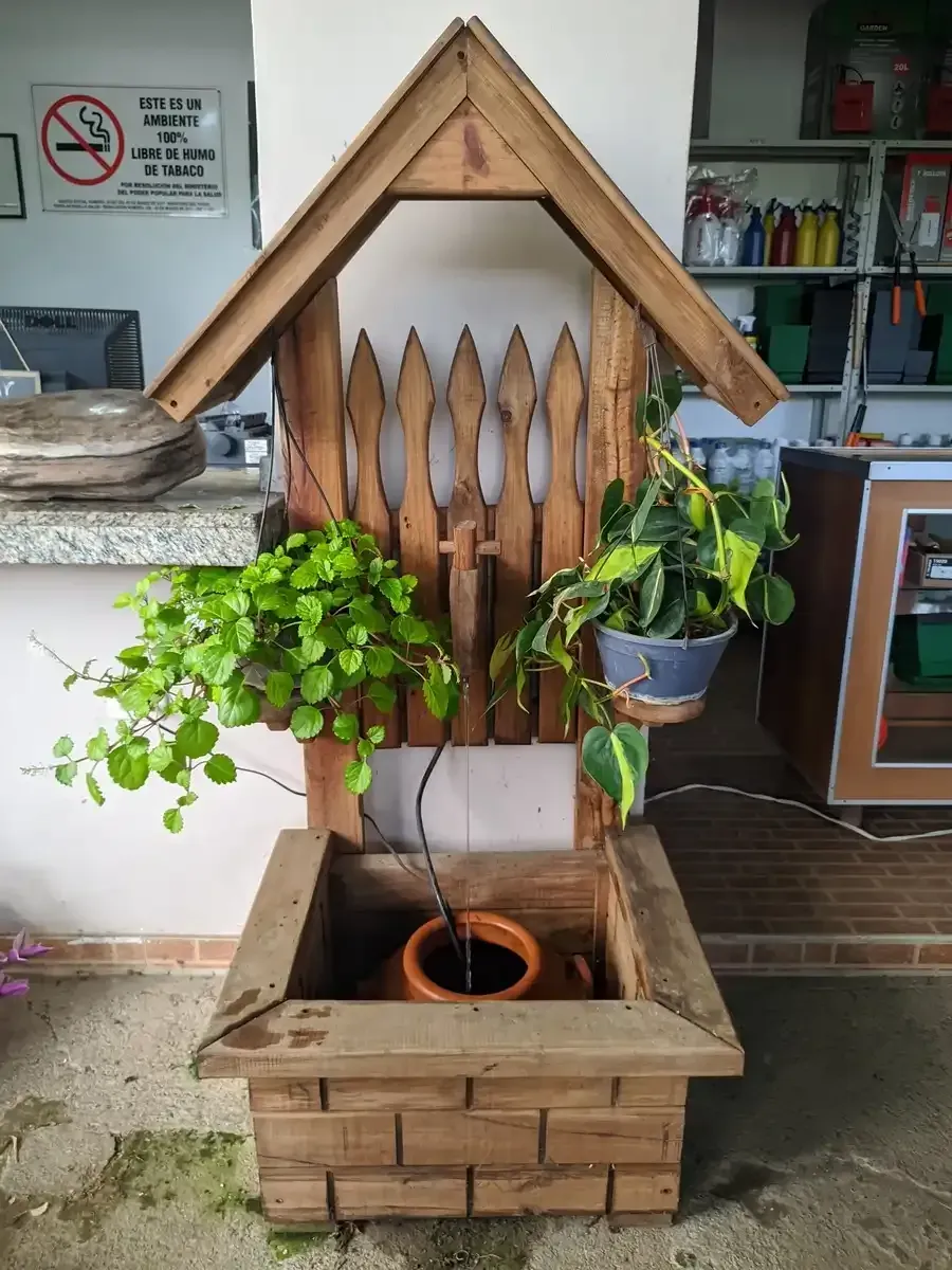 Una fuente de madera con una planta en maceta en su interior.
