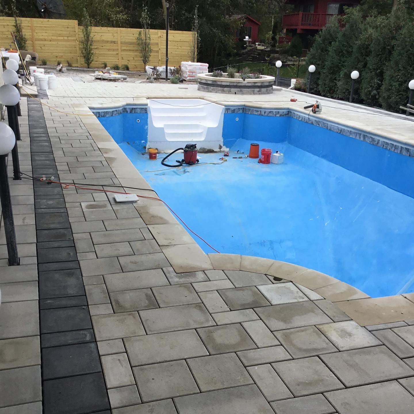 Pool under construction; blue interior, stone patio, and white stairs.