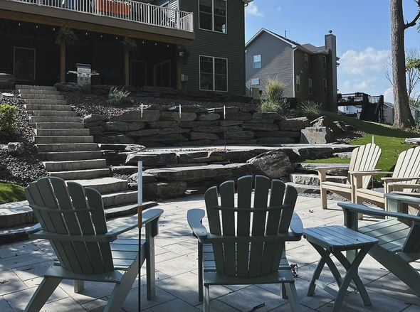 Backyard patio with Adirondack chairs, stone steps, and a tiered wall.