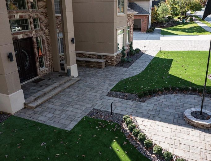 Brick path leading to a house with a manicured lawn and landscaping; sunny day.