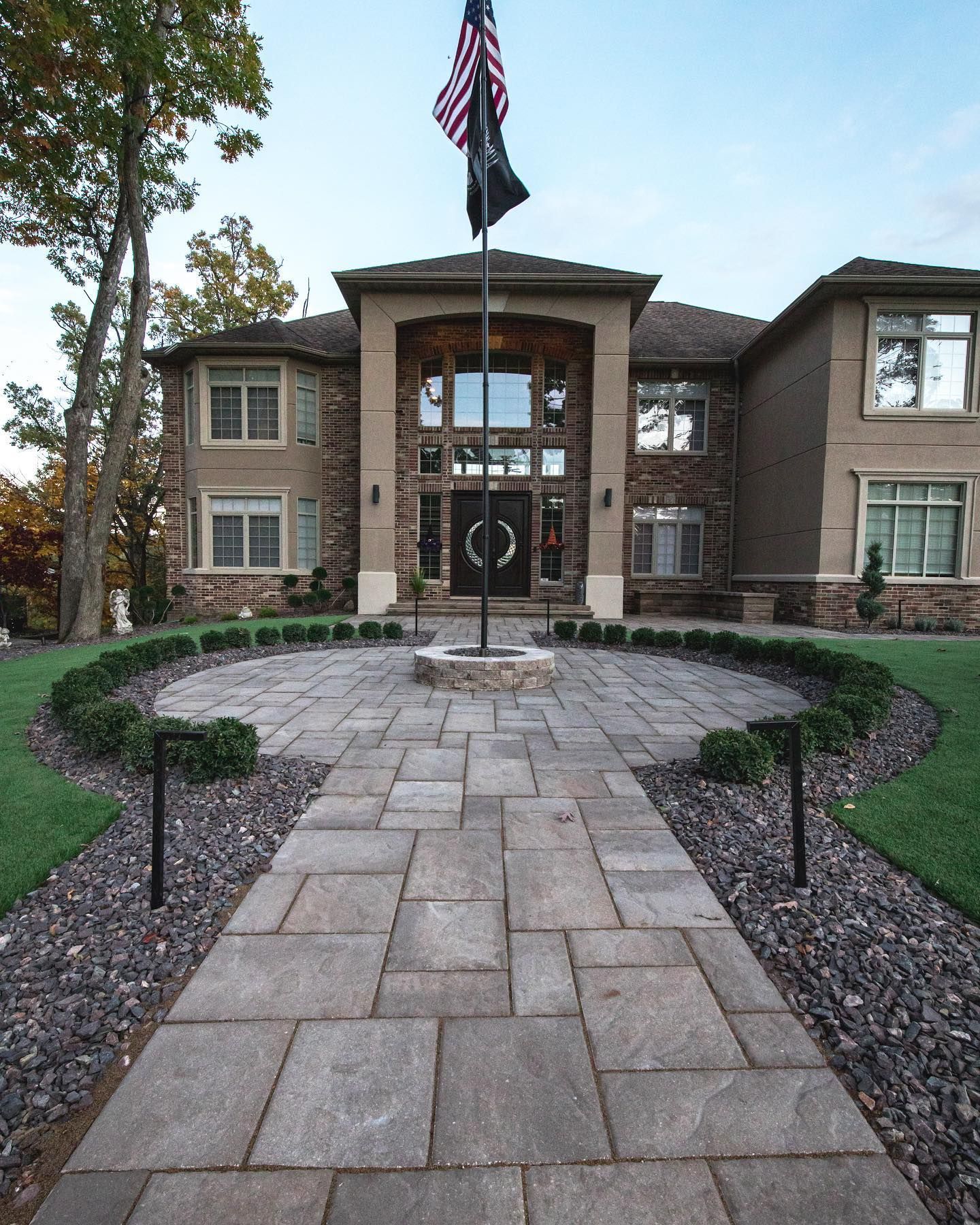 Flagged home entrance with brick pathway and manicured landscape.