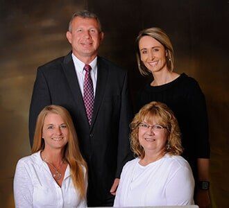 Four people, two seated and two standing, pose for a professional group photo.