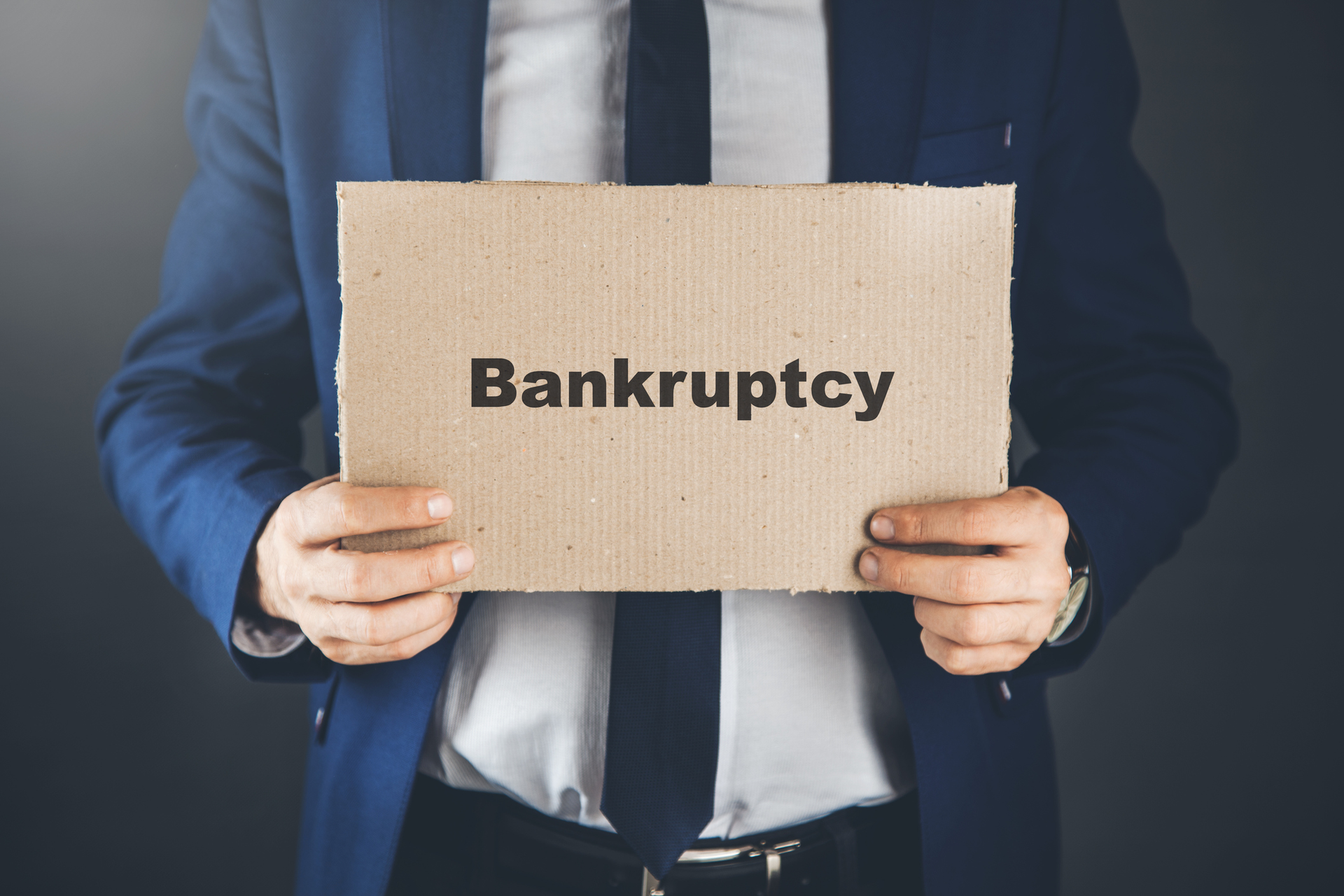 Bankruptcy lawyer holding paper with bankruptcy text, offering legal help to clients in debt.