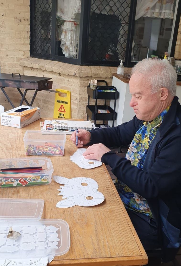 A man is sitting at a table making a mask.