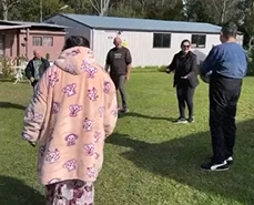 A group of people are standing in a circle on a lush green field.