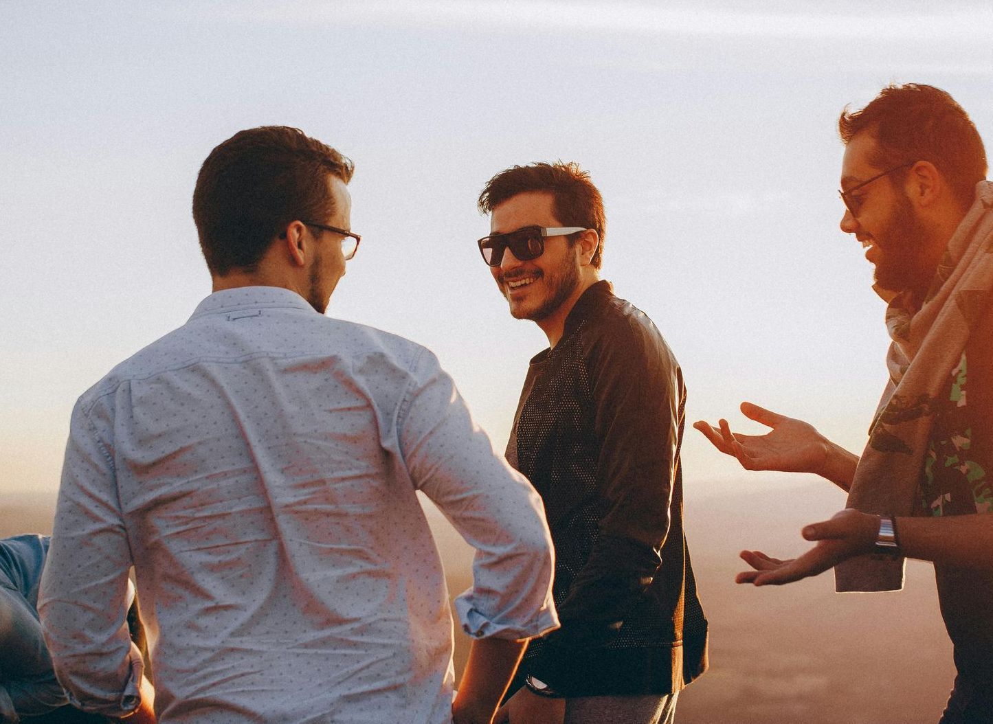 Three men are standing on top of a hill talking to each other.