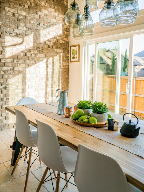 A dining room with a long wooden table and white chairs.