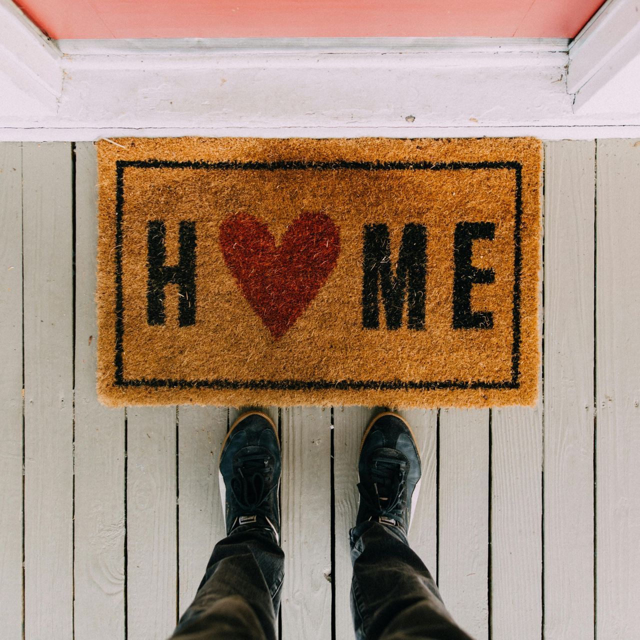 A person standing on a door mat that says home