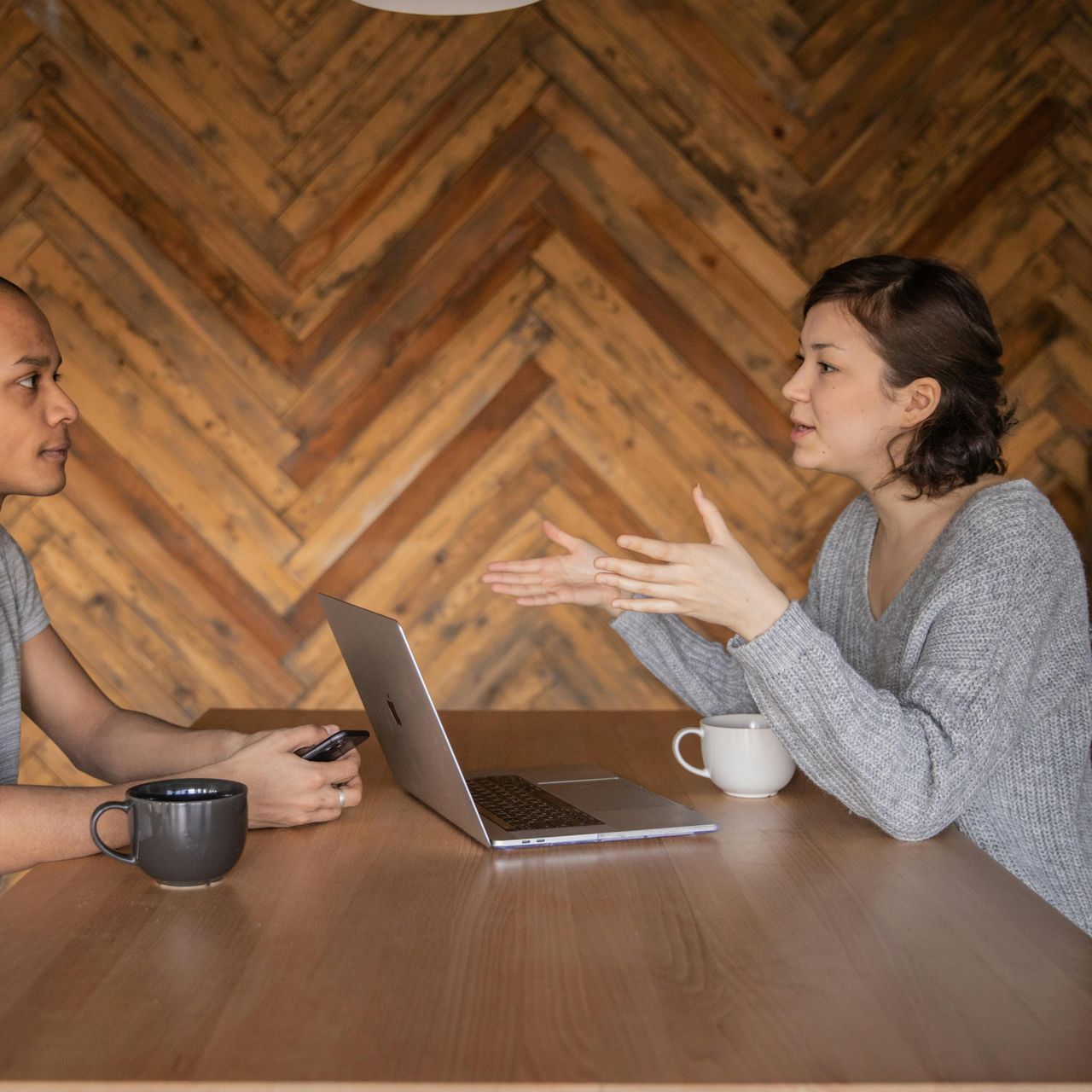 A man and a woman are sitting at a table with a laptop