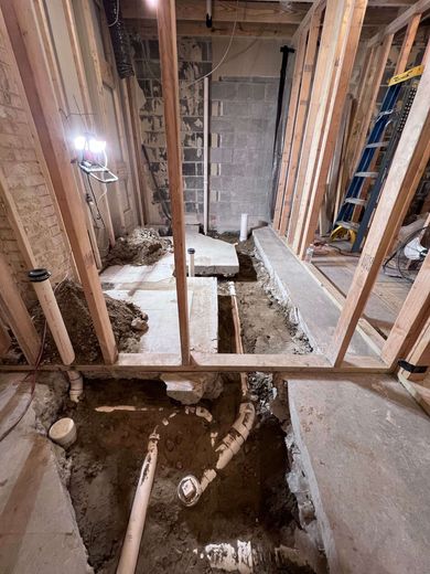 Construction site with exposed plumbing and framing for a bathroom renovation.