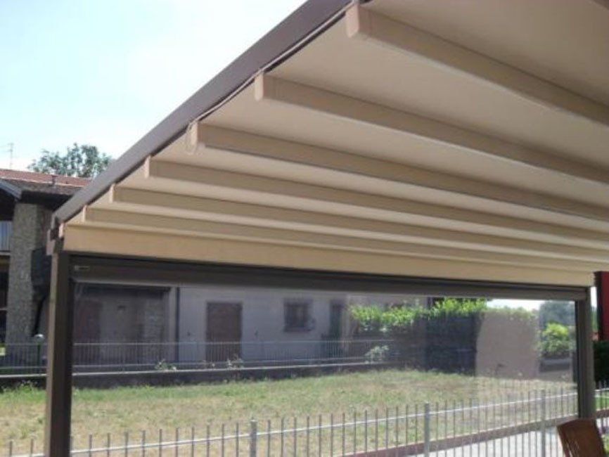 tettoia in legno scuro con tenda motorizzata
