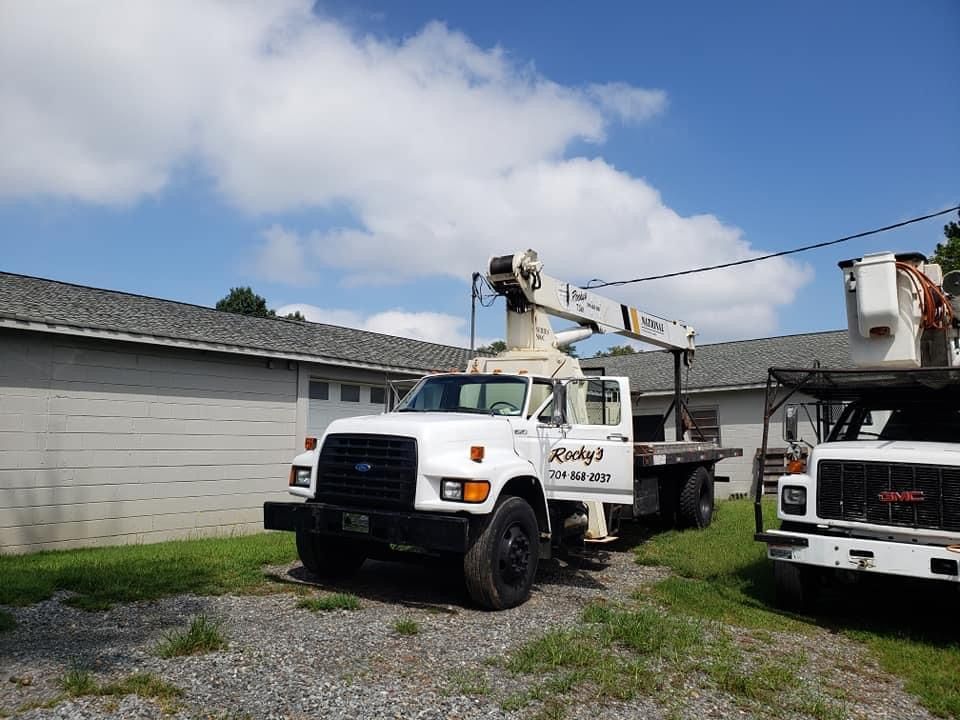 A White Truck With A Crane On Top Of It Is Parked In Front Of A Building — Gastonia, NC — Rocky's Tree Service