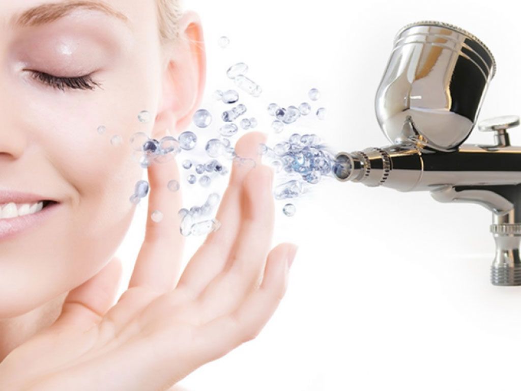 Il viso di una donna viene spruzzato d'acqua da un aerografo.