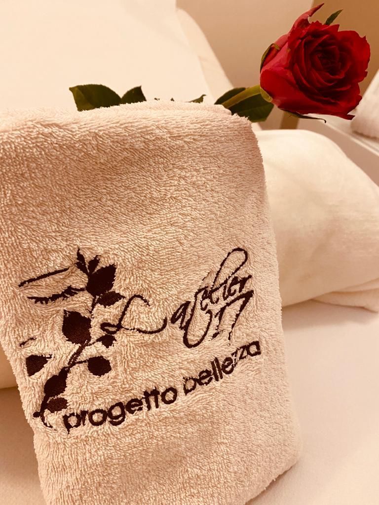 Un asciugamano è appoggiato sul letto accanto a una rosa rossa.