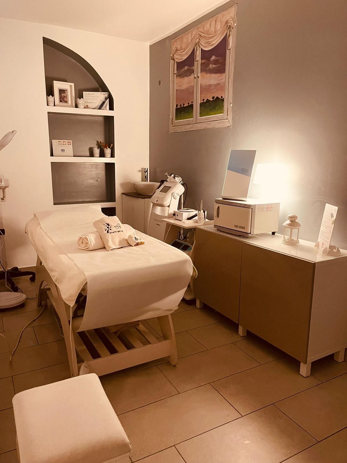 Una stanza con un lettino per massaggi e una finestra sul muro.