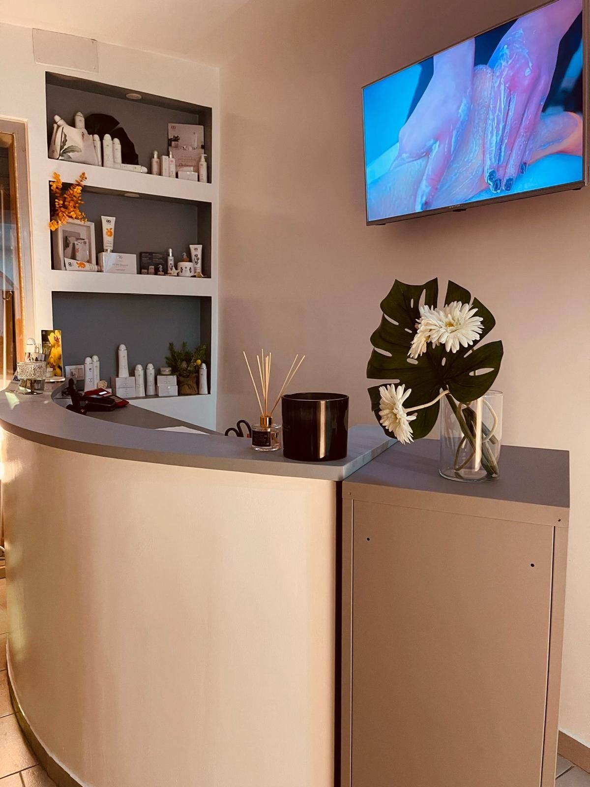 Un bancone della reception in un salone con una TV sulla parete soprastante.