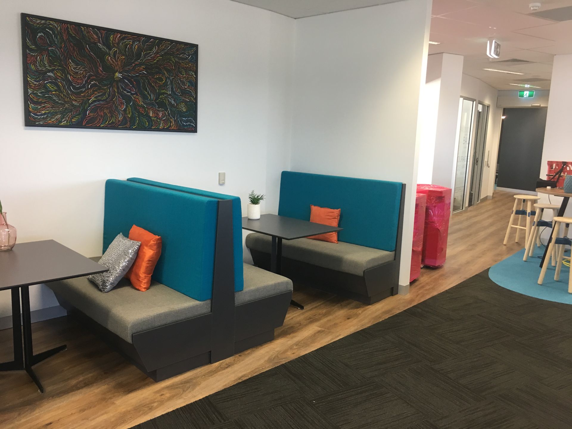 Lounge area with teal booths, grey cushions, and small tables. A painting hangs on the wall, and the floor has both wood and carpet — AKW Builders Pty Ltd In Leanyer, NT