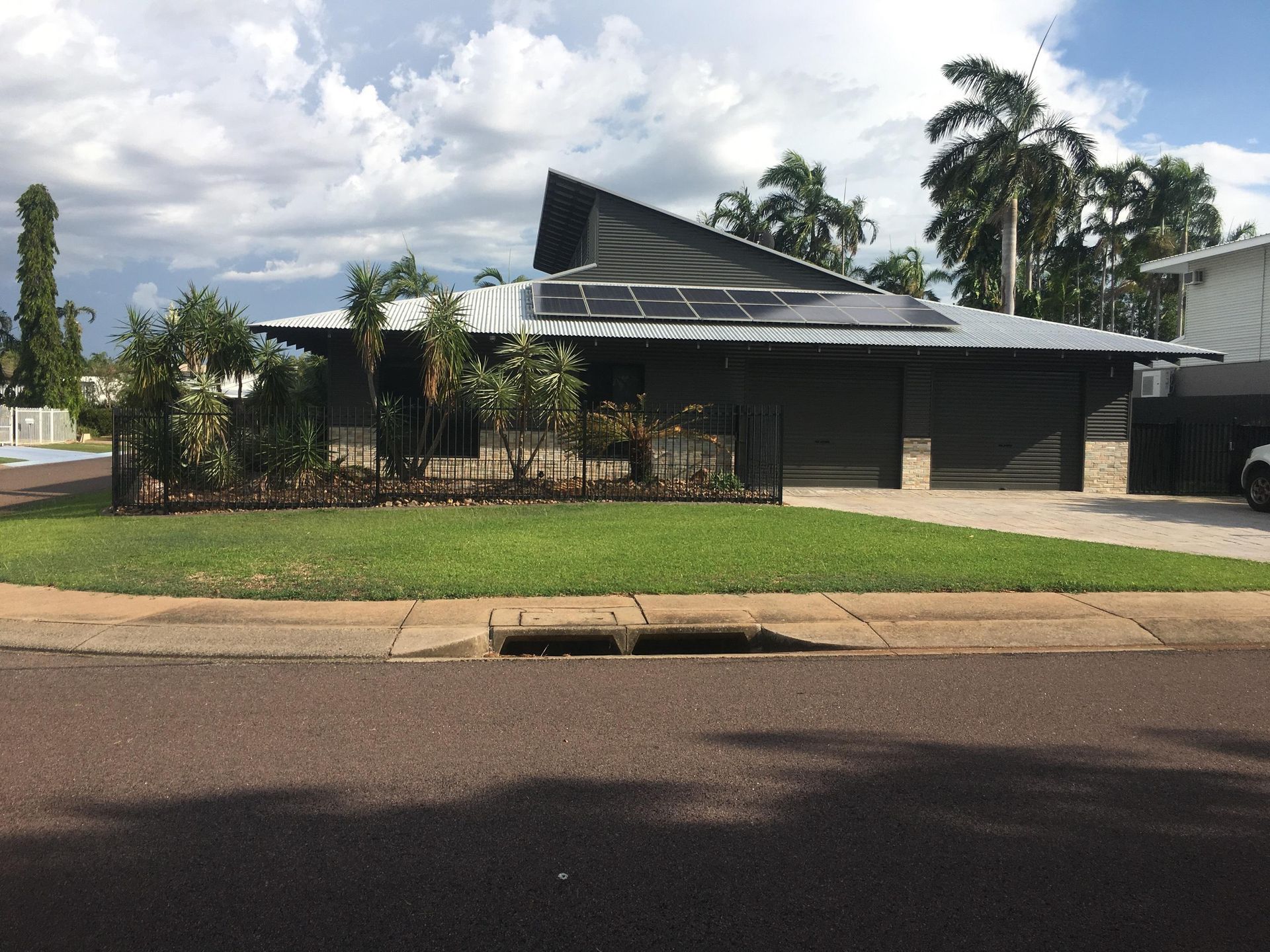 Modern house with dark grey exterior, solar panels, and a well-kept lawn — AKW Builders Pty Ltd In Leanyer, NT