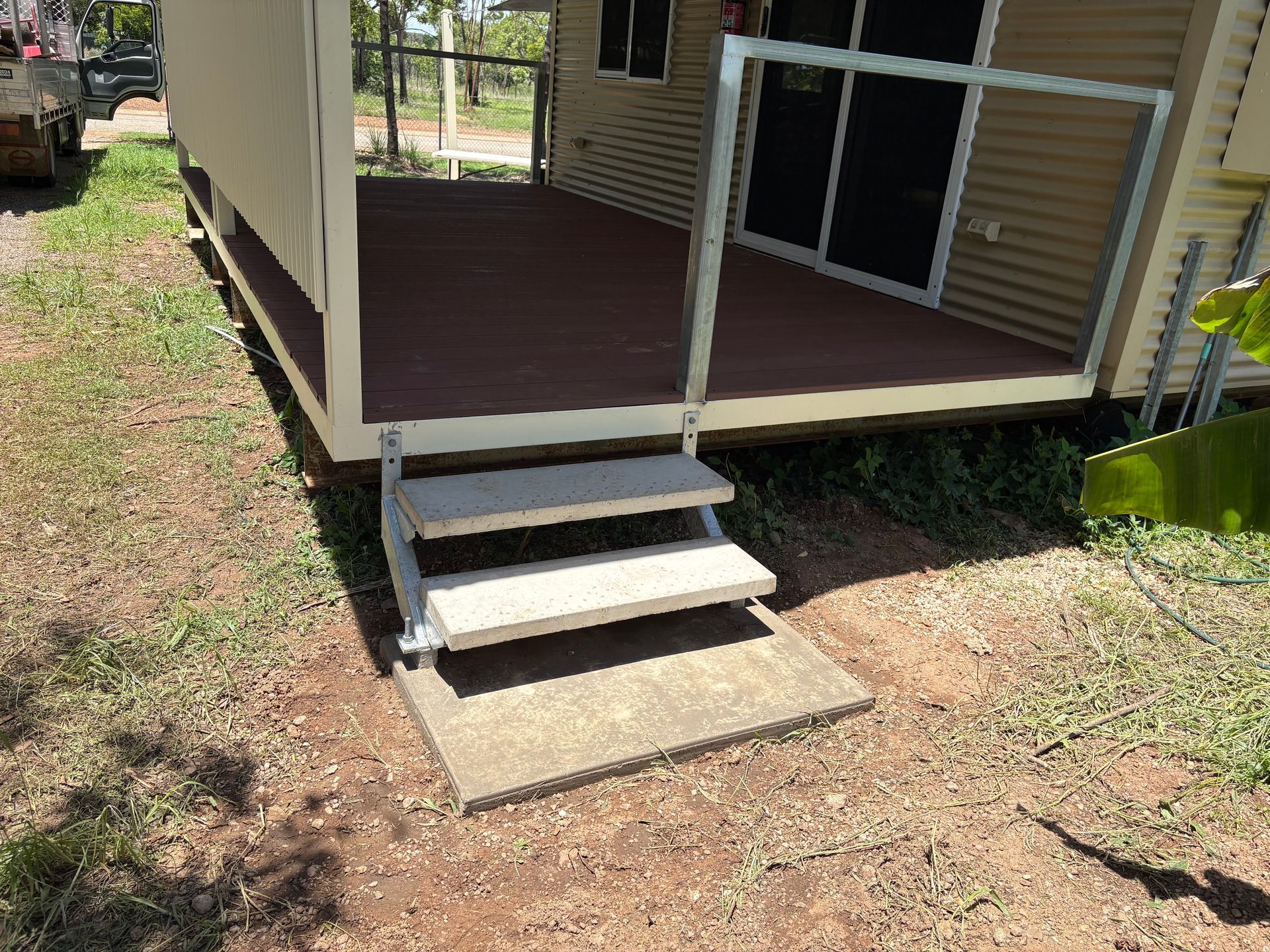 A house with a small deck and steps. Steps are made of concrete, railing is metal. Green grass — AKW Builders Pty Ltd In Leanyer, NT