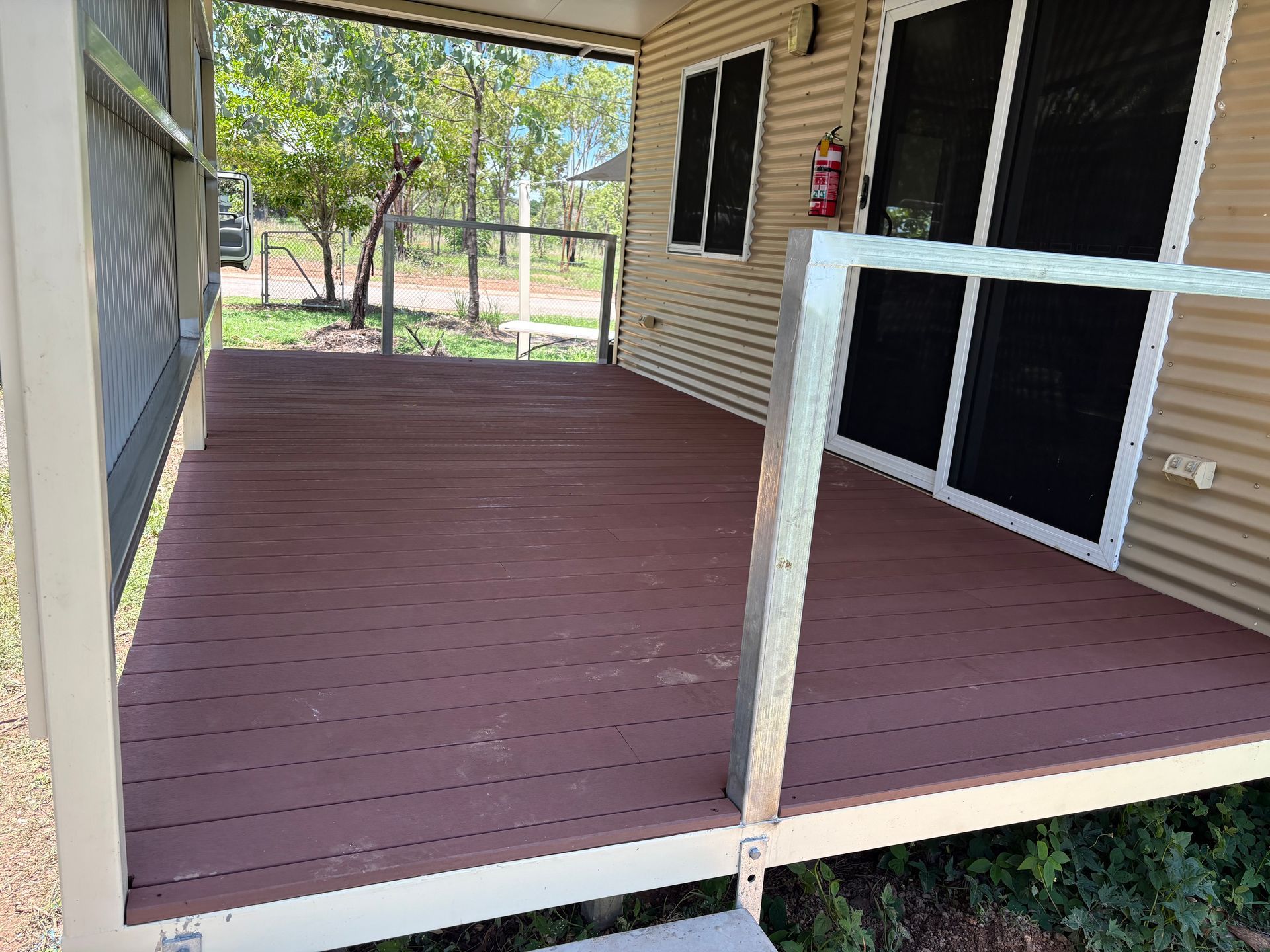 Covered wooden porch with railings, brown deck, and metal siding — AKW Builders Pty Ltd In Leanyer, NT