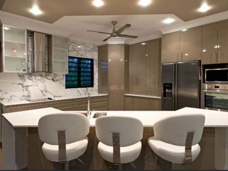 Modern kitchen with white island, three bar stools, and stainless steel appliances — AKW Builders Pty Ltd In Leanyer, NT