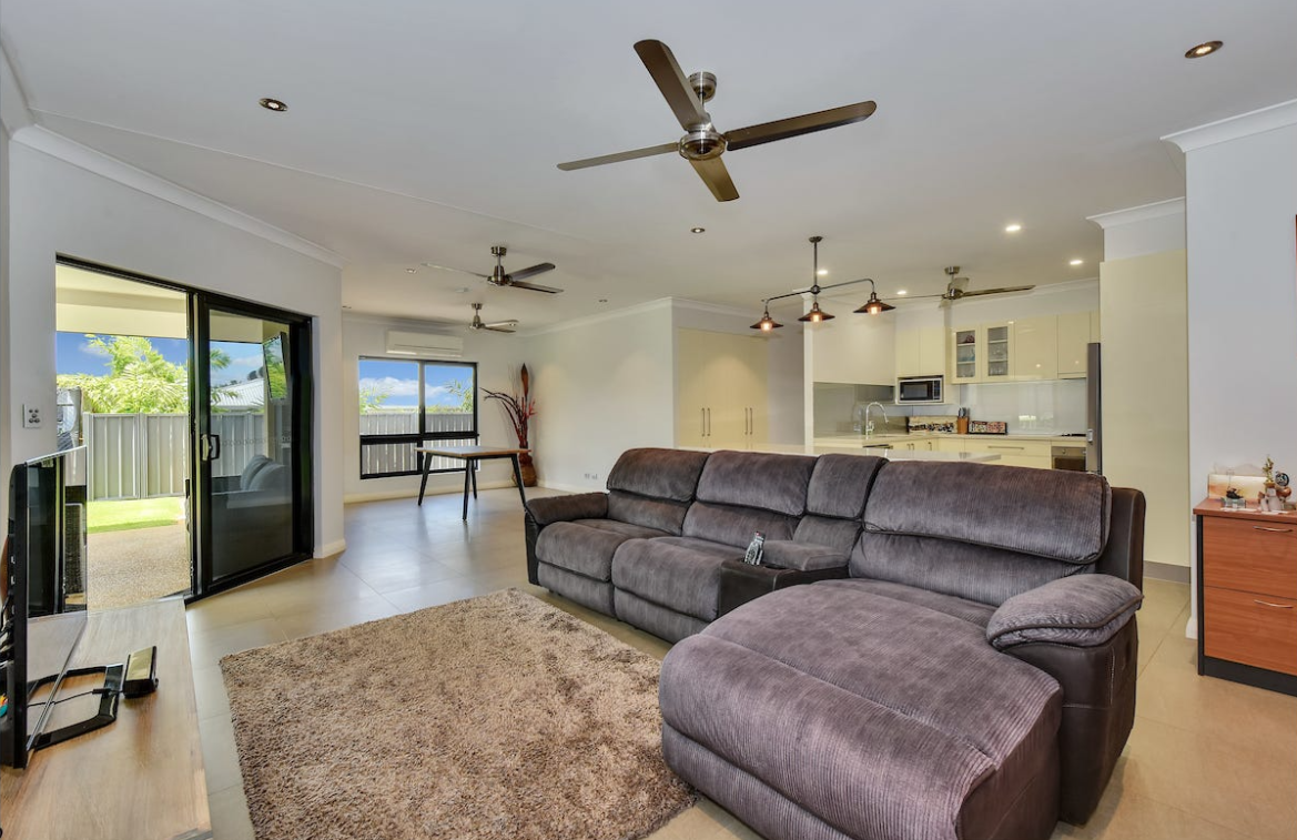 Living room with a brown sectional, rug, and sliding glass door — AKW Builders Pty Ltd In Leanyer, NT