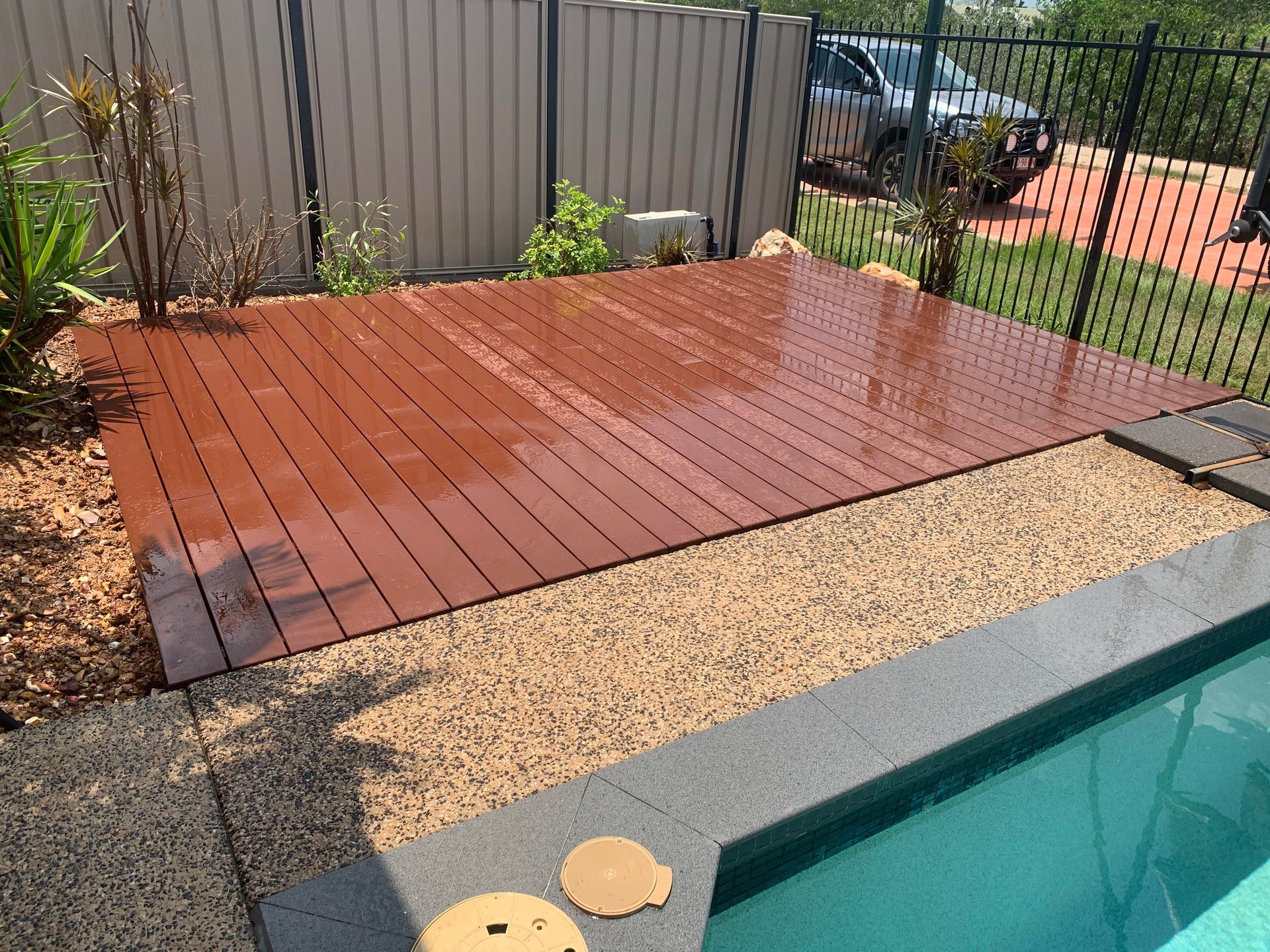 Wooden deck next to a pool with gravel border, backed by fence and plants — AKW Builders Pty Ltd In Leanyer, NT