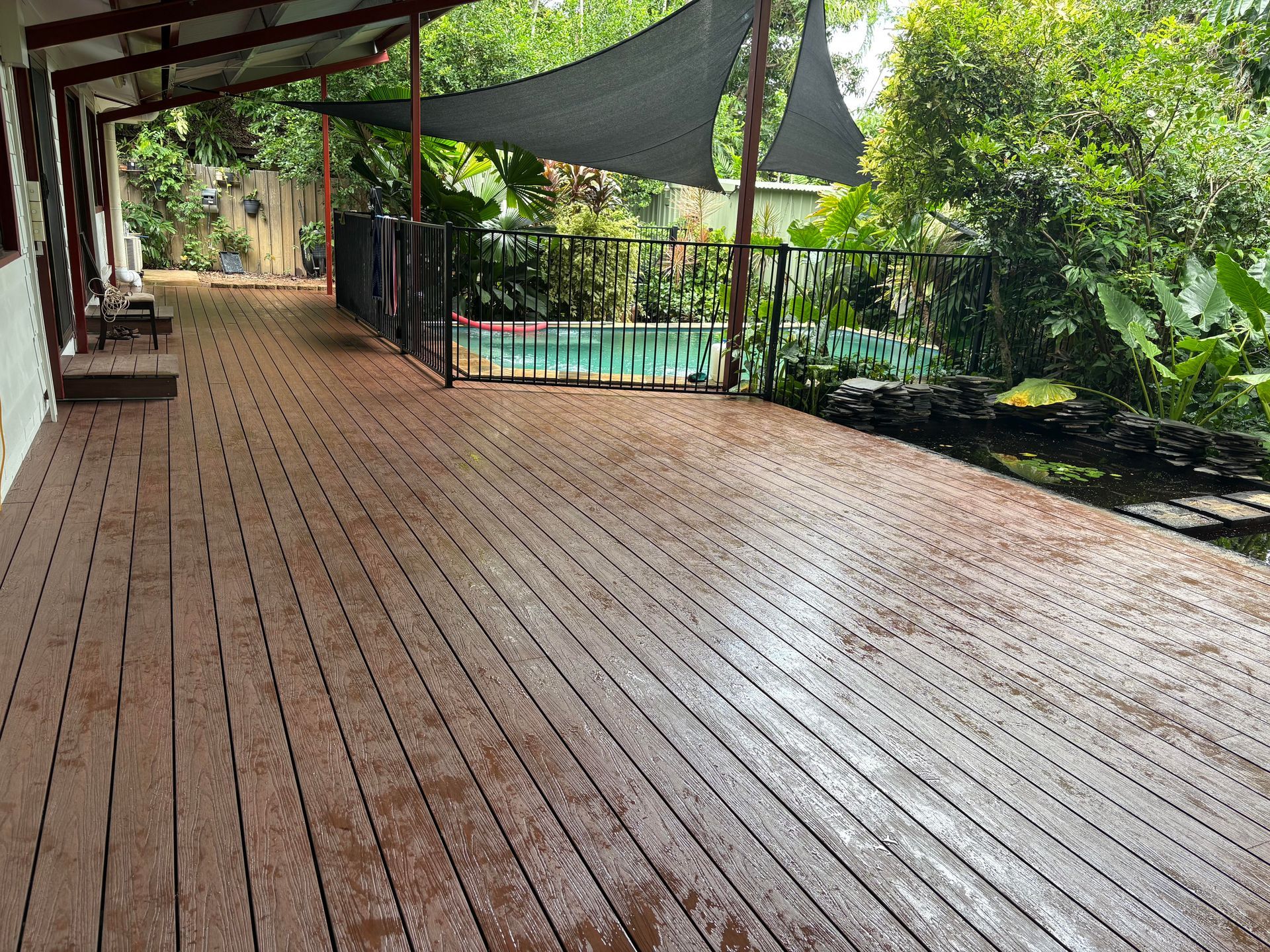 Wooden deck with a covered area, fence, and pool in a lush, green backyard — AKW Builders Pty Ltd In Leanyer, NT