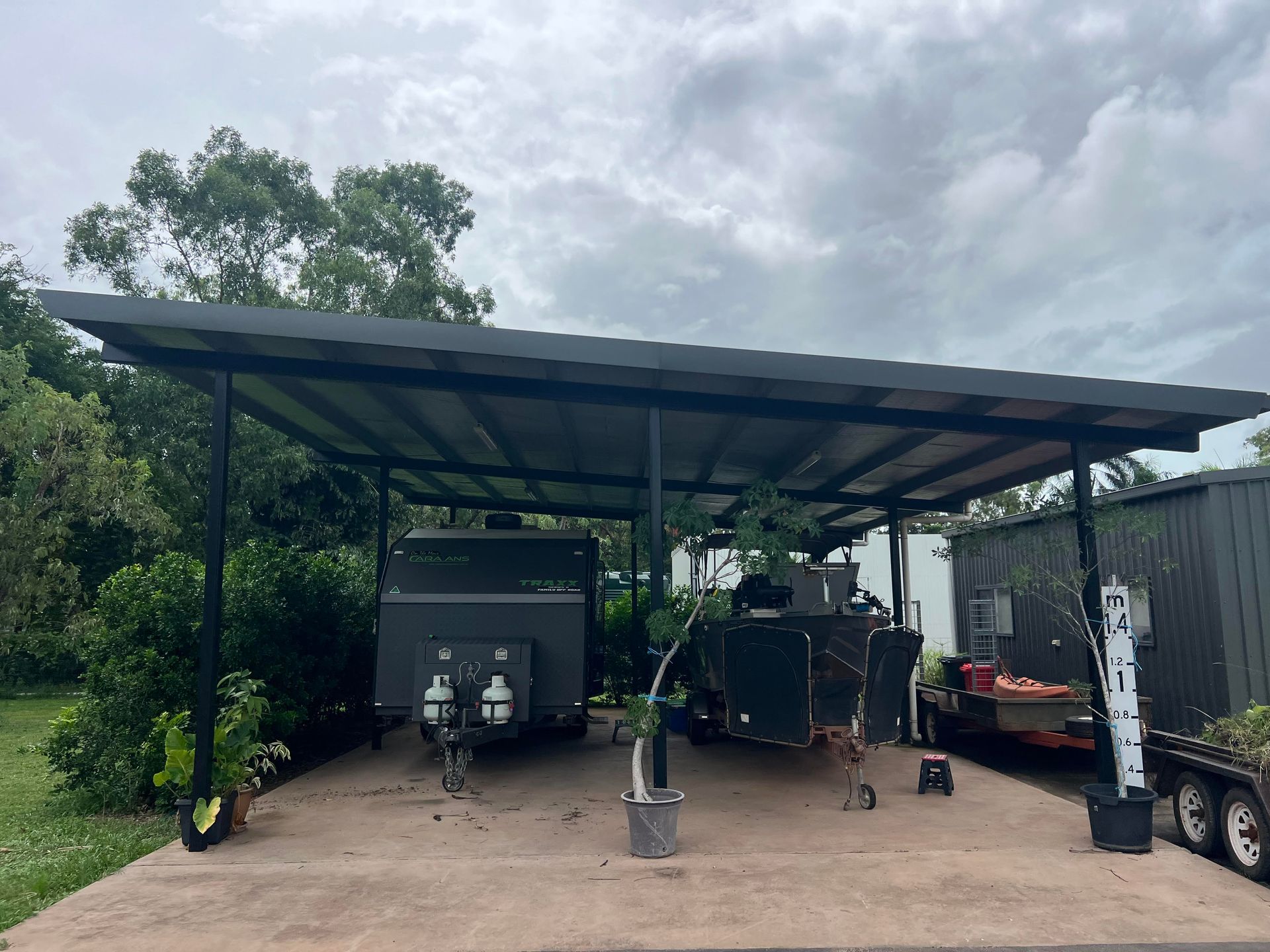 Carport shelters two trailers on concrete pad, under a cloudy sky — AKW Builders Pty Ltd In Leanyer, NT