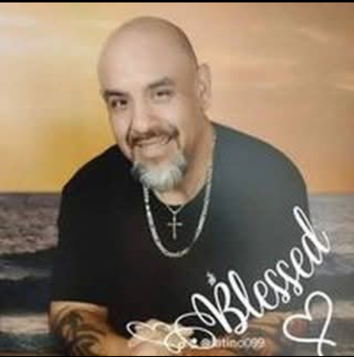 A woman is sitting at a desk with a laptop and a vase of flowers.