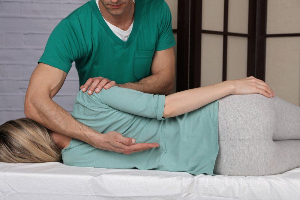 A man standing over a women, providing spinal decompression services.