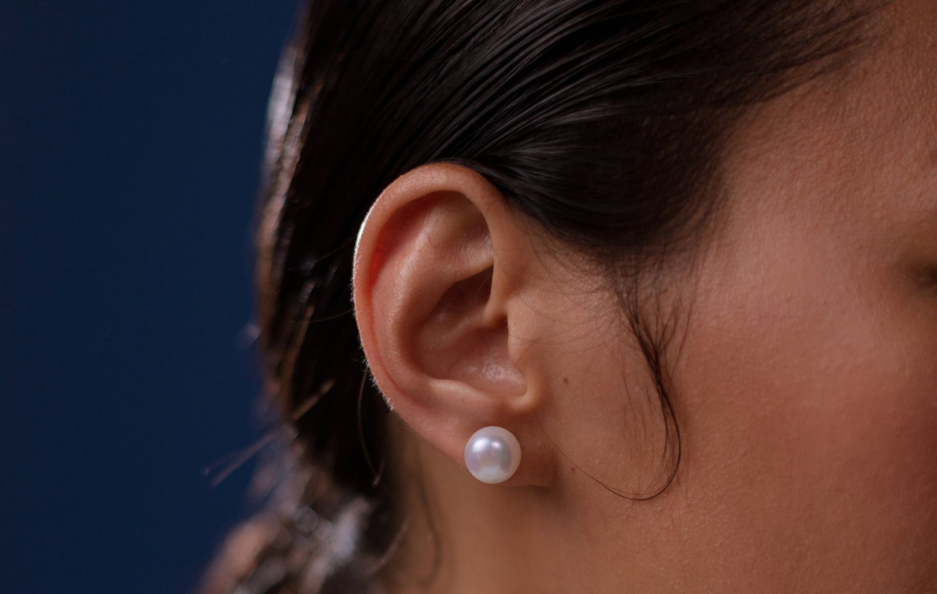 A persons ear with pearl earrings