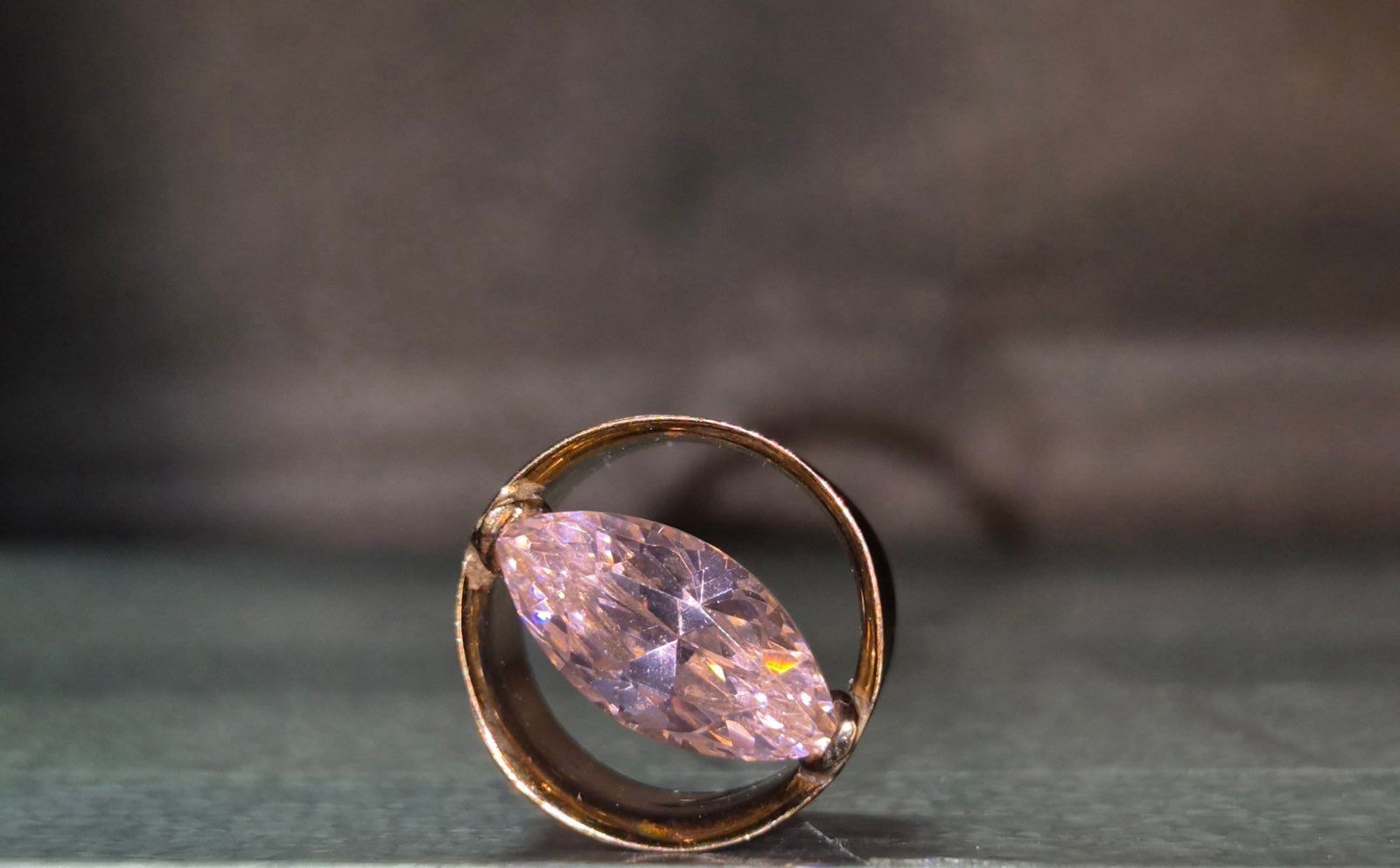 A gold ring with a marquise-cut, light purple gem set inside a circular band.