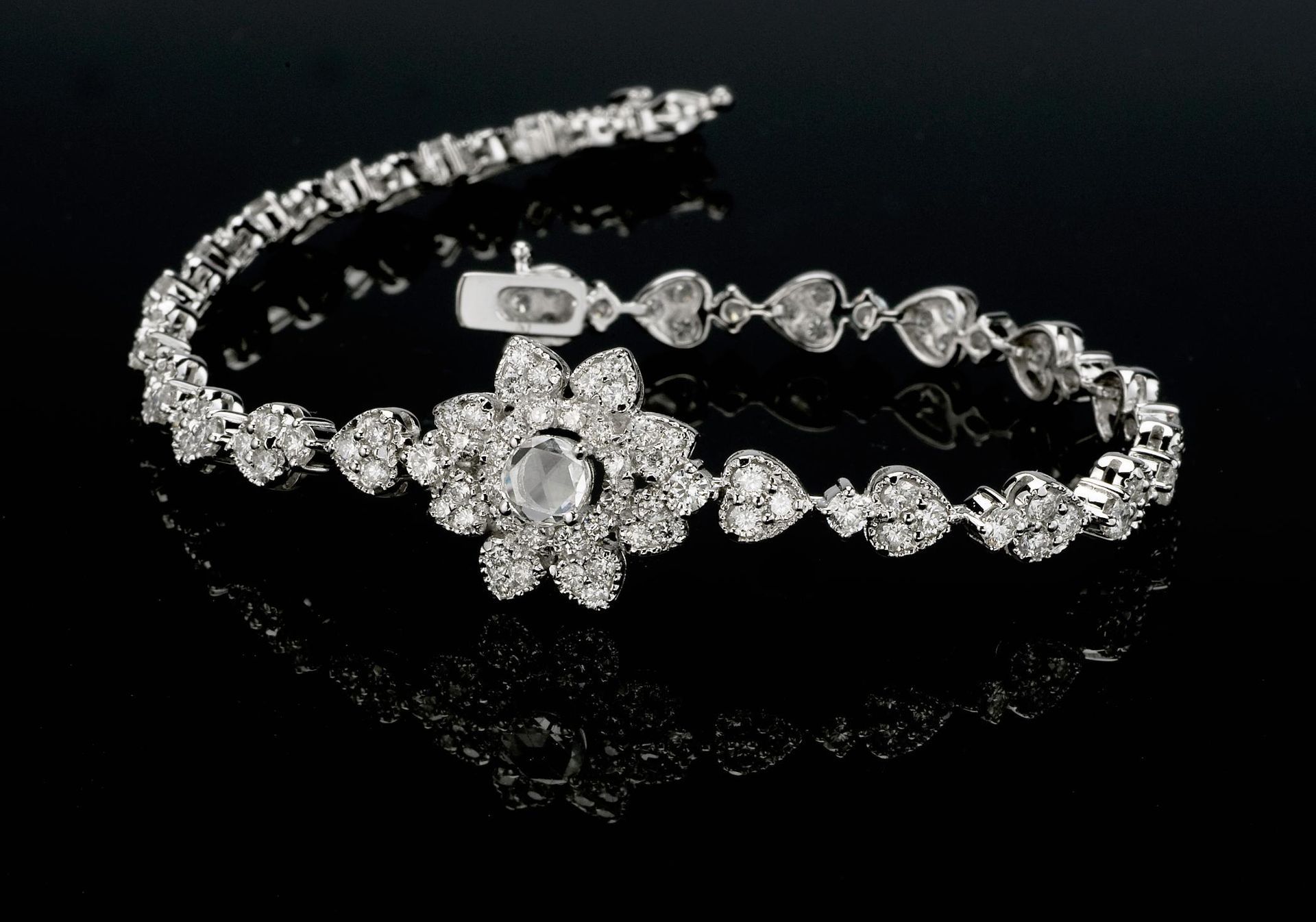 Diamond bracelet with a floral-shaped centerpiece, set against a black background.