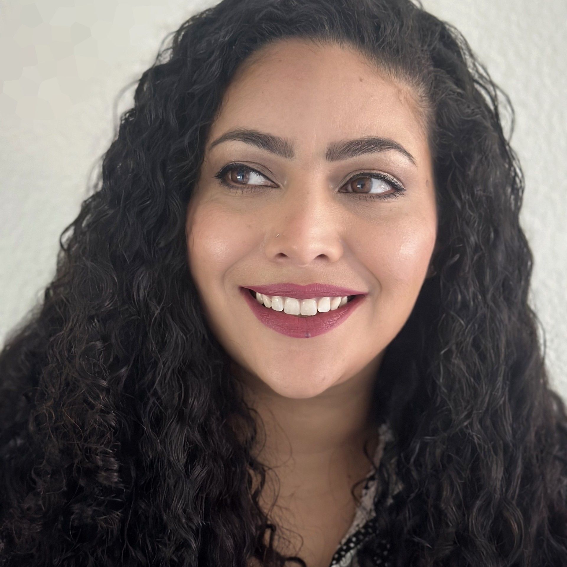 A woman with curly hair is smiling for the camera.