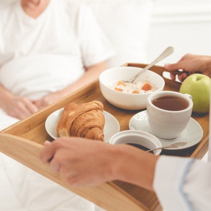 nurse bring tray of food to patient